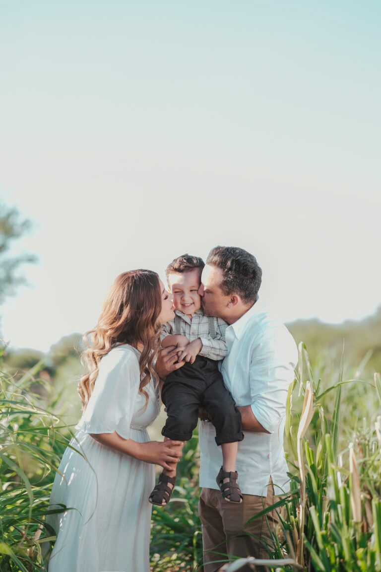 A family standing in a field of tall grass hugging.
